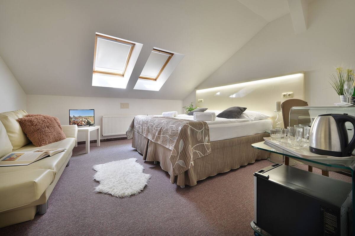 Un dormitorio moderno con cama, sofá, una mesita y una cafetera.