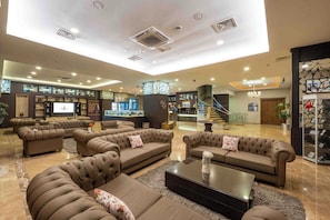 A spacious lobby with multiple seating areas, a staircase, and a reception desk.
