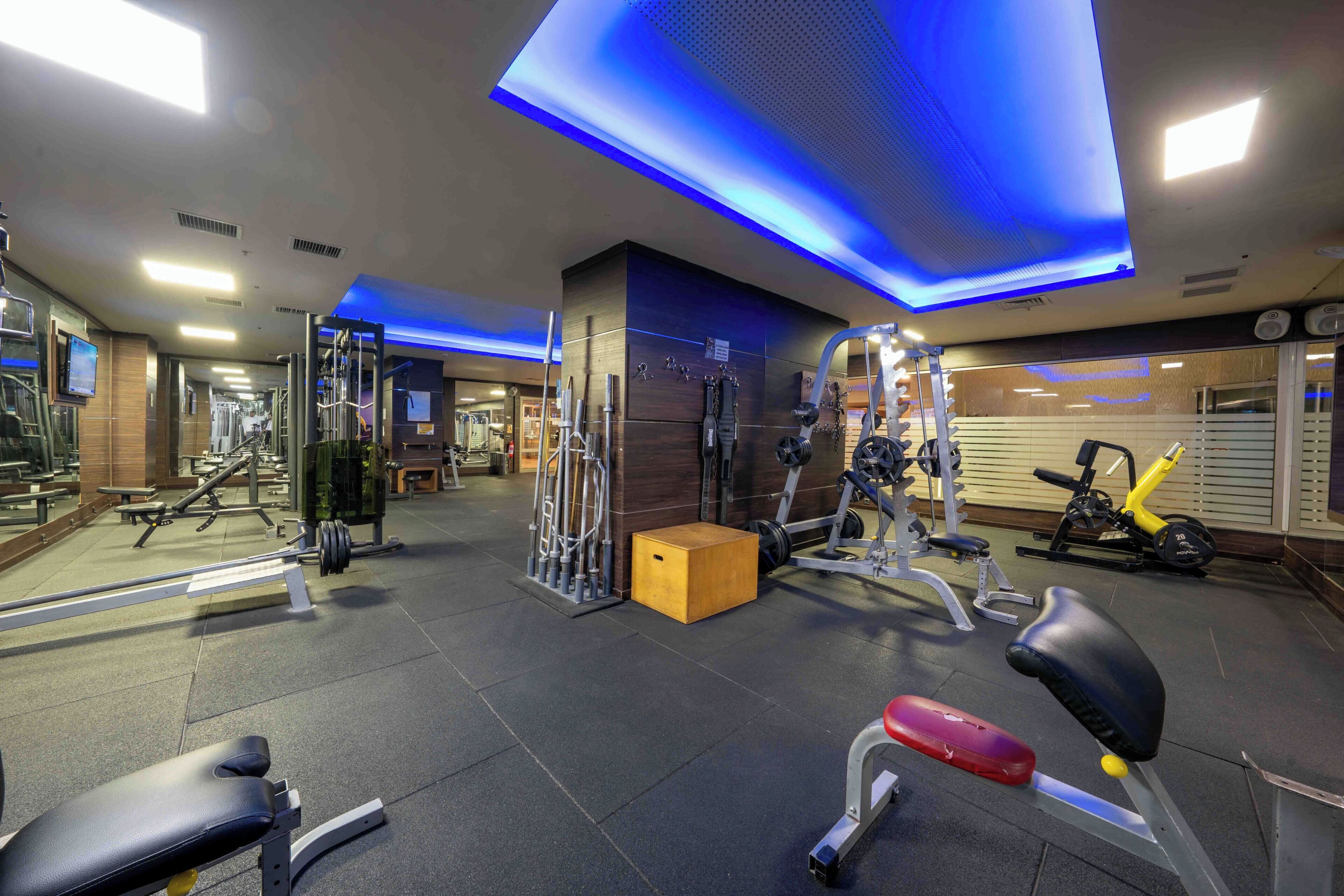 A gym with exercise equipment, benches, and a mirrored wall.