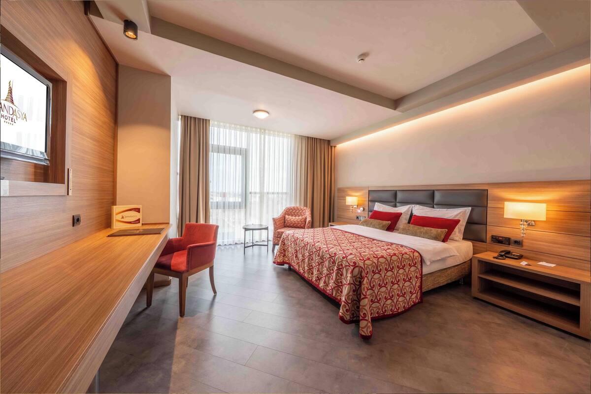 Ein modernes Hotelzimmer mit Bett, Schreibtisch, Stuhl und Blick auf die Stadt.