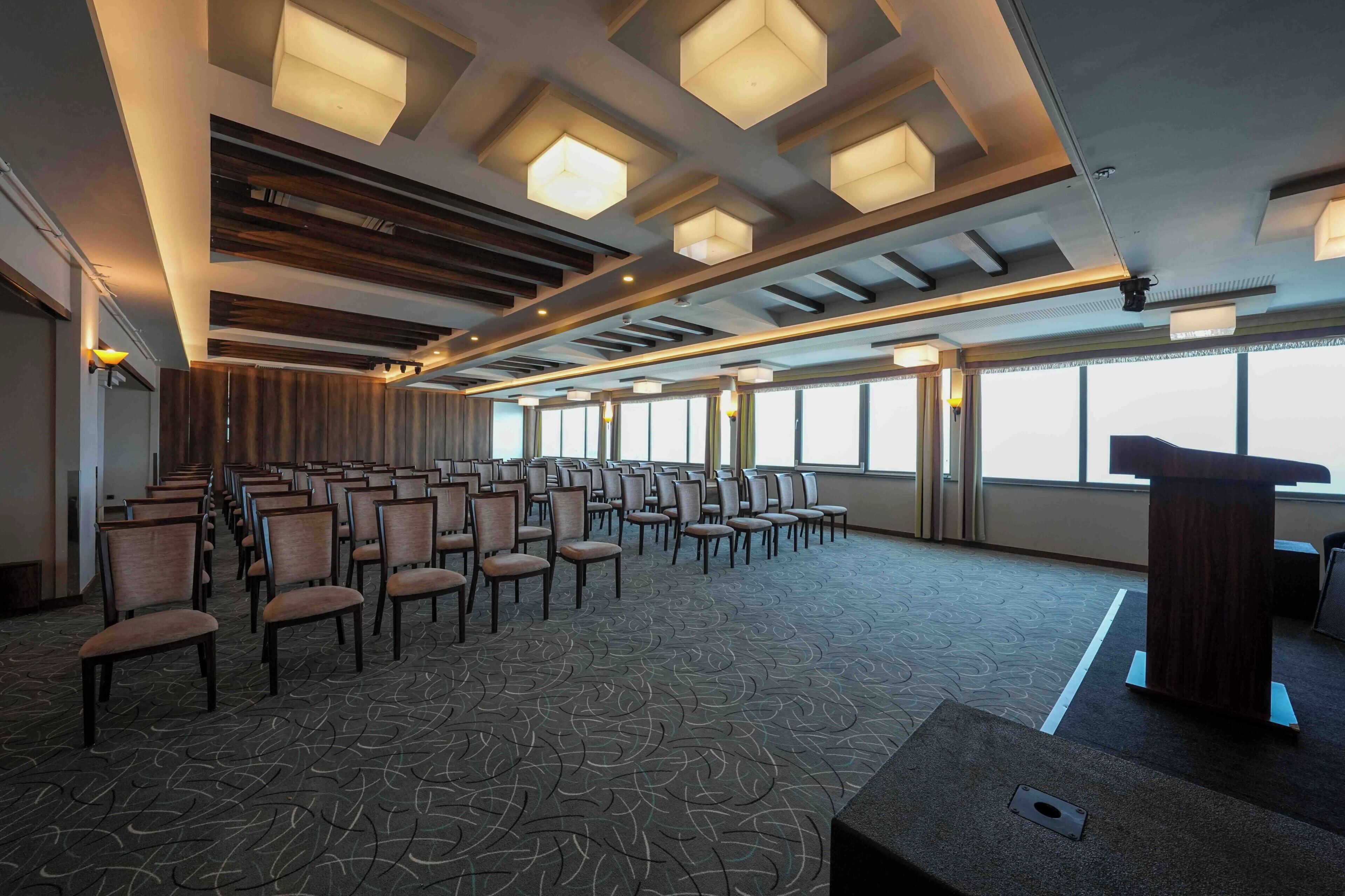 A conference room with rows of chairs, a podium, and large windows.