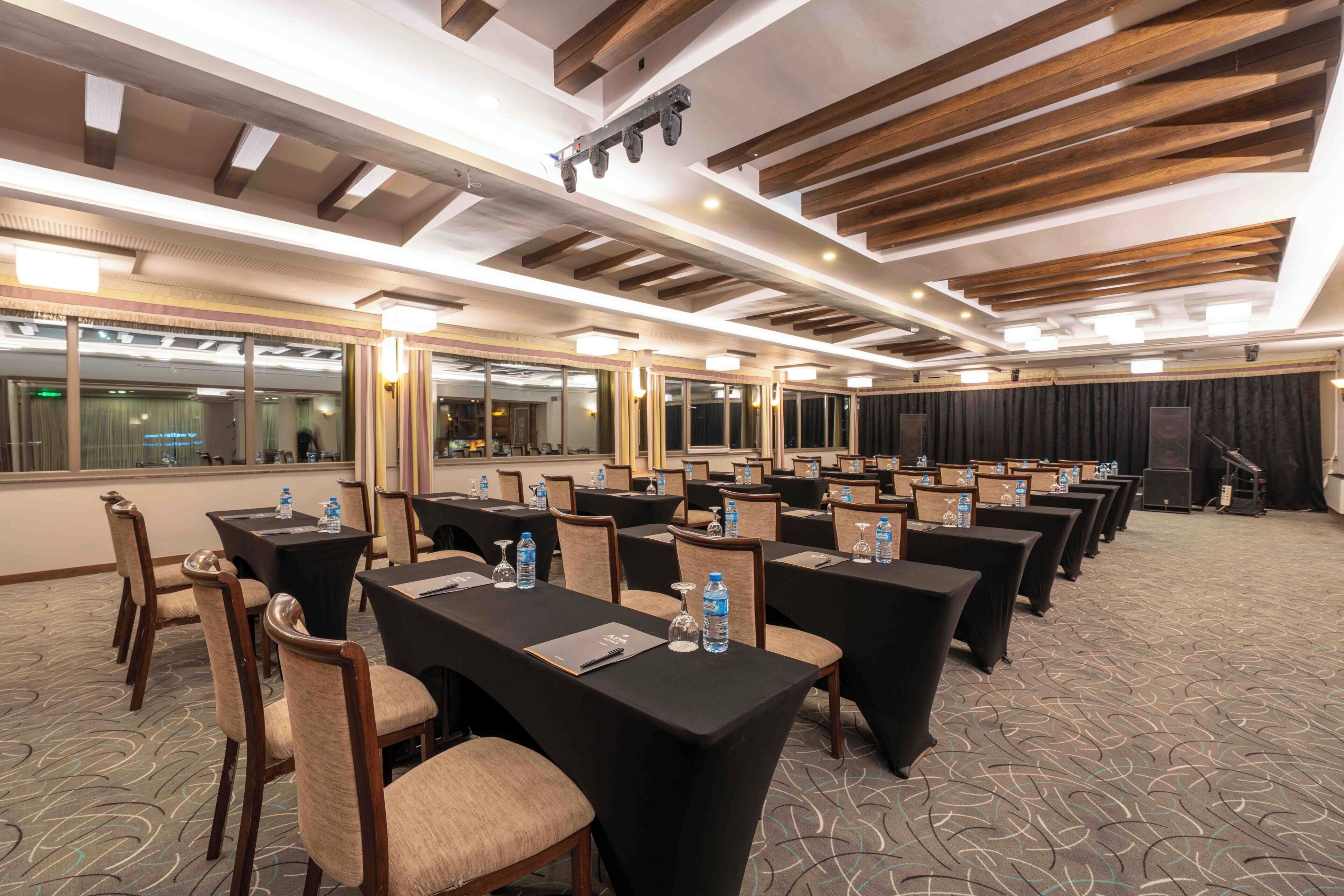 A conference room with tables, chairs, and a stage.