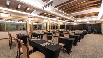 A conference room with tables, chairs, and a stage.