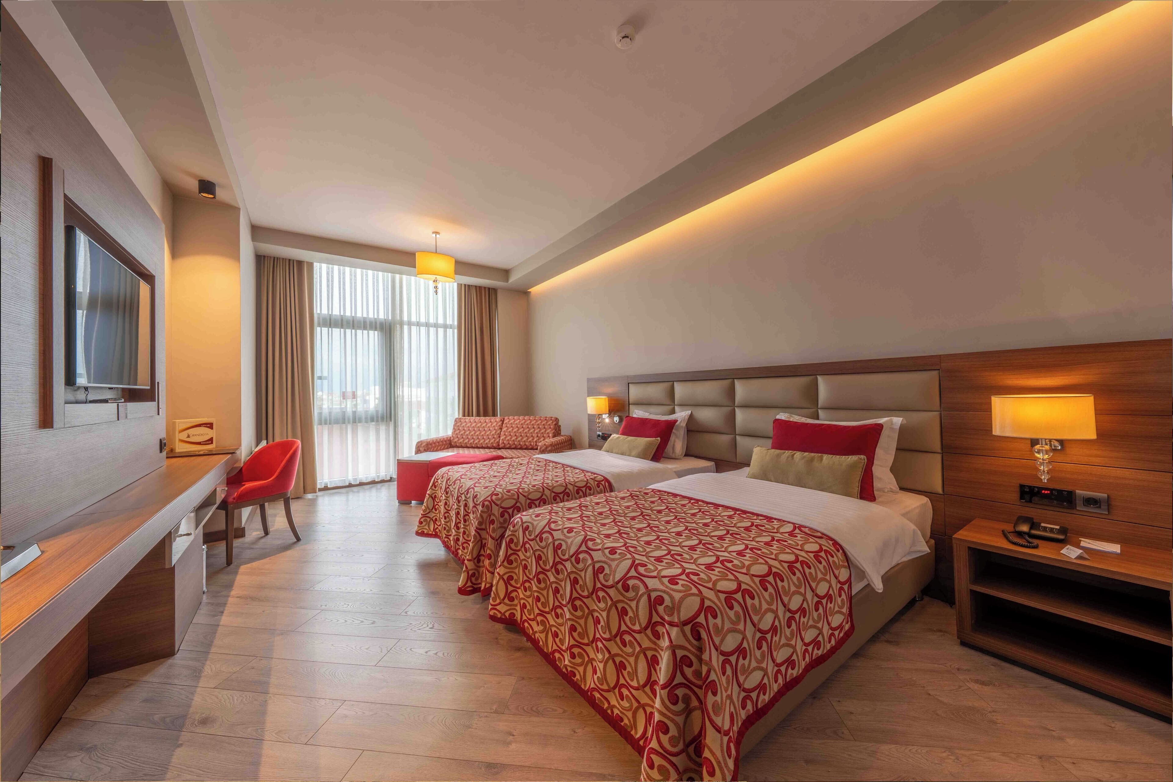 A hotel room with a bed, a desk, a chair, and a TV.