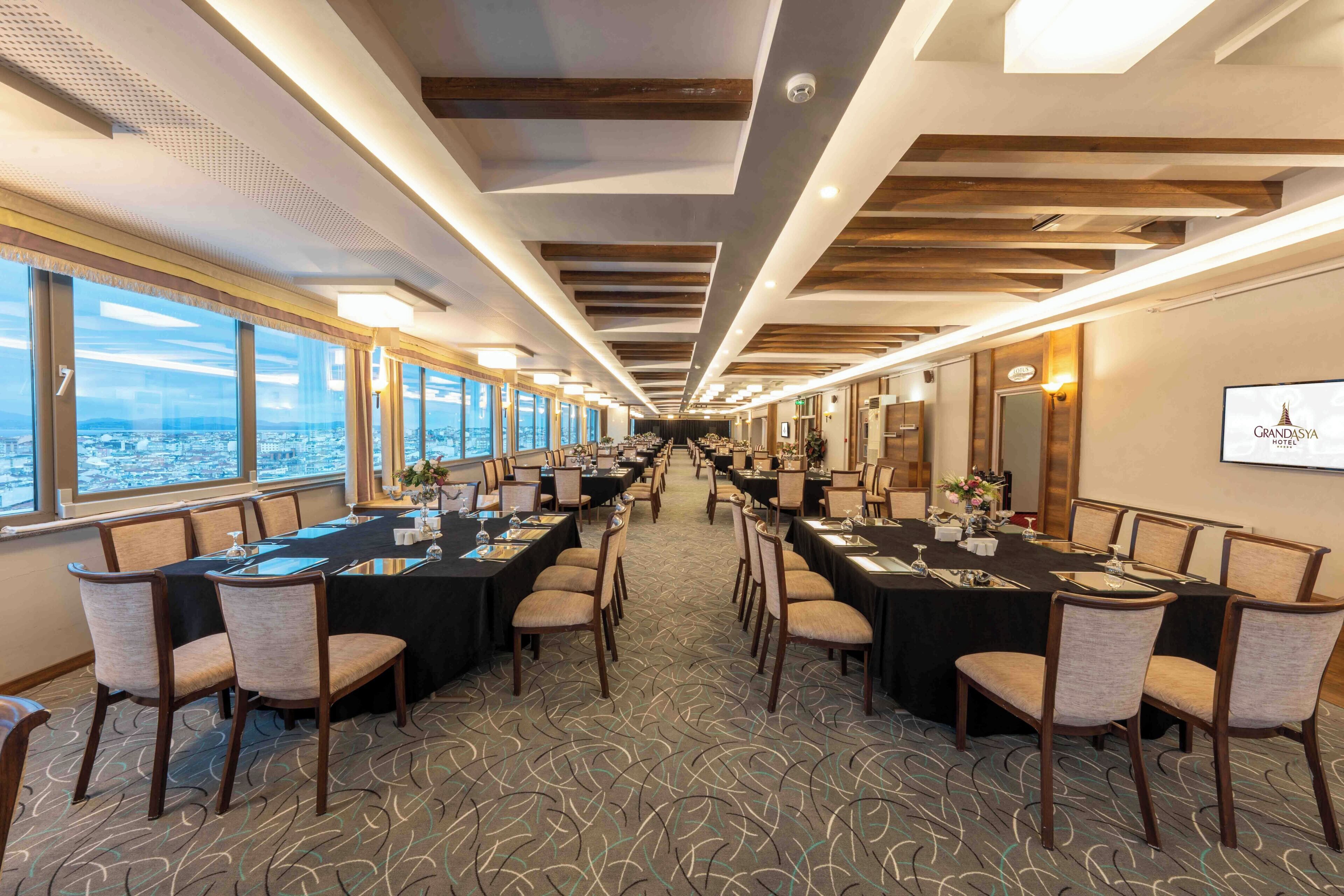 A conference room with tables and chairs, large windows, and a city view.