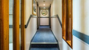 A hallway with a blue carpet, wooden doors, and a mirror on the wall. - George Oxford Hotel (Oxford)