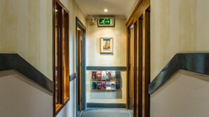 A hallway with a carpeted floor, wooden doors, and a framed picture on the wall. - George Oxford Hotel (Oxford)
