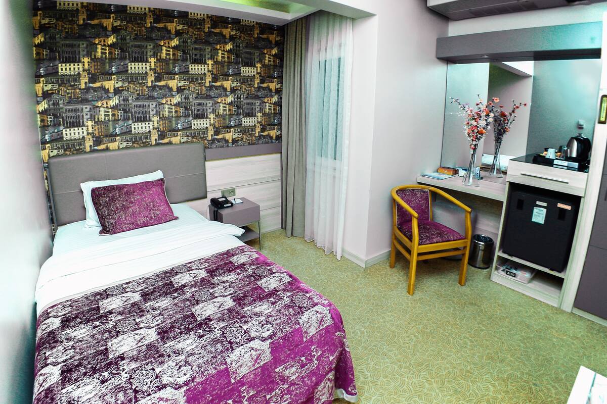 Una habitación de hotel con cama, escritorio, silla, espejo y pared con diseño.
