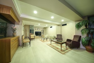 Un salón amplio con un aparador de madera, televisor, zona de comedor y una planta grande en maceta.