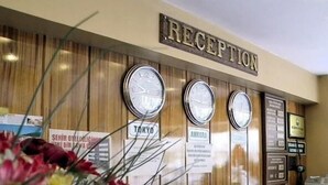 Un espace d’accueil avec une pancarte indiquant « RÉCEPTION », trois horloges et quelques affiches d’information.
