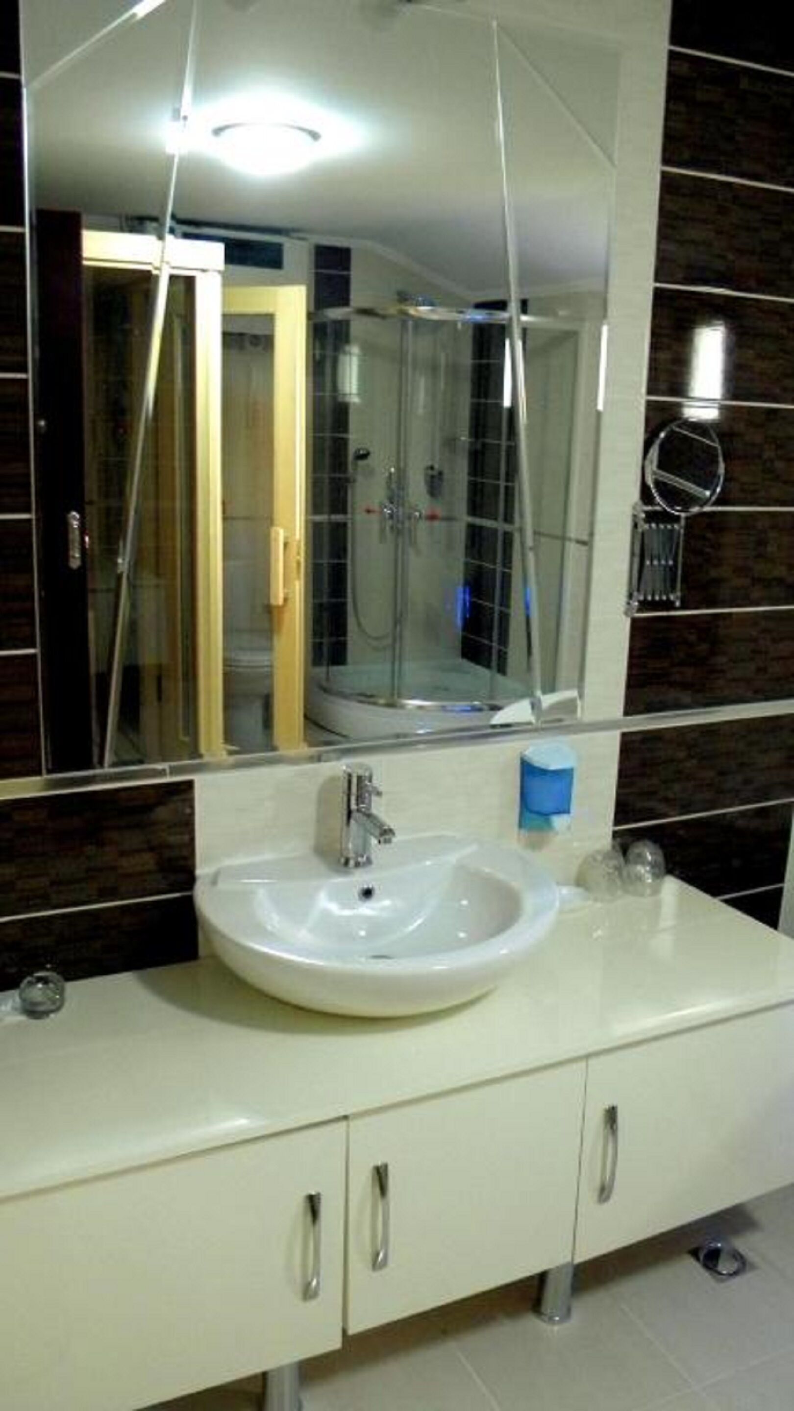 Un baño con un espejo grande, un lavabo y una cabina de ducha.