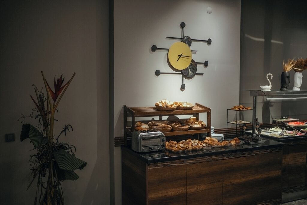 A buffet setup with various food items, a wall clock, and a decorative plant.