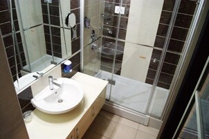 Un baño moderno con lavamanos blanco, cabina de ducha de vidrio y espejo.