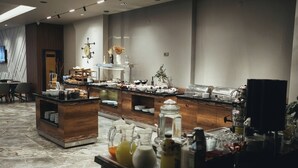 Un área de desayuno moderno en un hotel, con un sistema de bufé que incluye diversas opciones de comida y bebidas.