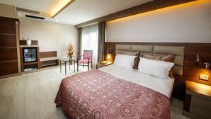 Habitación de hotel con una cama grande, mesitas de noche, un escritorio, una silla y un minibar.