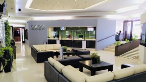 Un vestíbulo moderno con mostrador de recepción, zona de estar y una escalera.