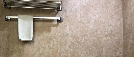 Une salle de bain avec des toilettes, un porte-serviettes sur lequel est pliée une serviette, et un mur recouvert de carreaux.