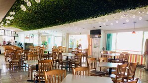 Un restaurante con mesas y sillas de madera, un techo verde y vistas a la calle.
