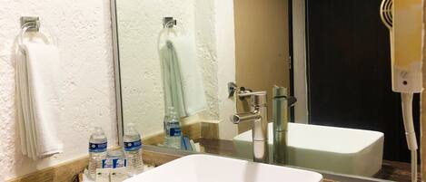A bathroom with a large mirror, a white sink, and a towel rack.