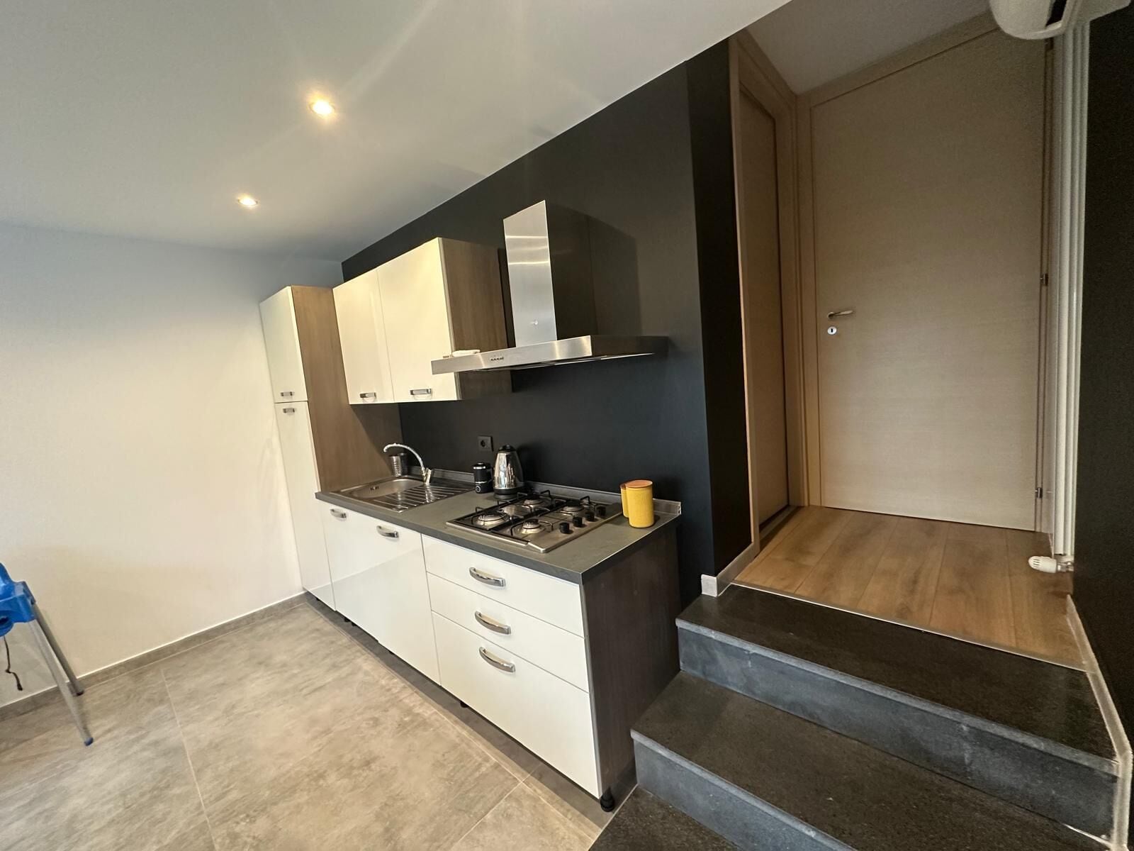 A modern kitchen with white cabinets, a gas stove, and a black countertop.
