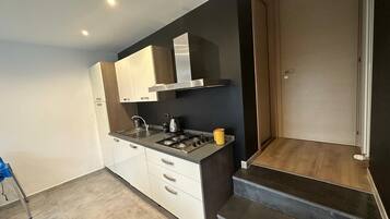A modern kitchen with white cabinets, a gas stove, and a black countertop.