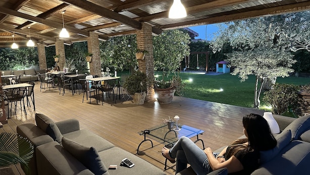 Un patio al aire libre con suelo de madera, zonas de estar e iluminación colgante.