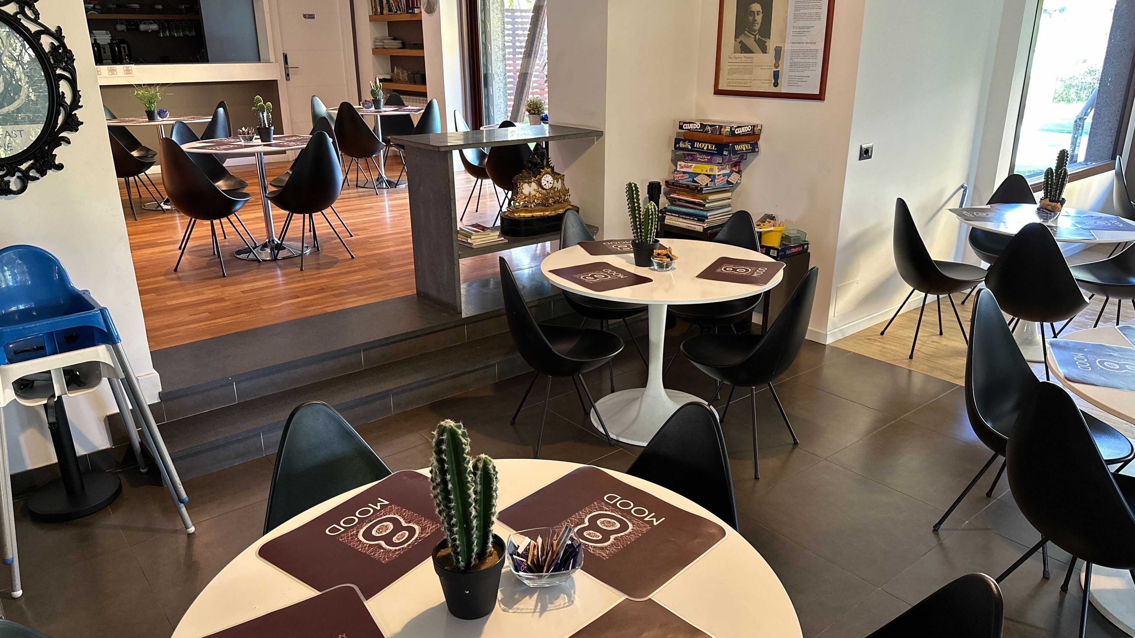 Un comedor moderno con mesas redondas, sillas negras y un reloj central.