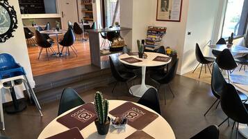 Un comedor moderno con mesas redondas, sillas negras y un reloj central.