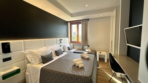 Una habitación de hotel moderna con dos camas, un televisor, una mesita y una ventana con cortinas.
