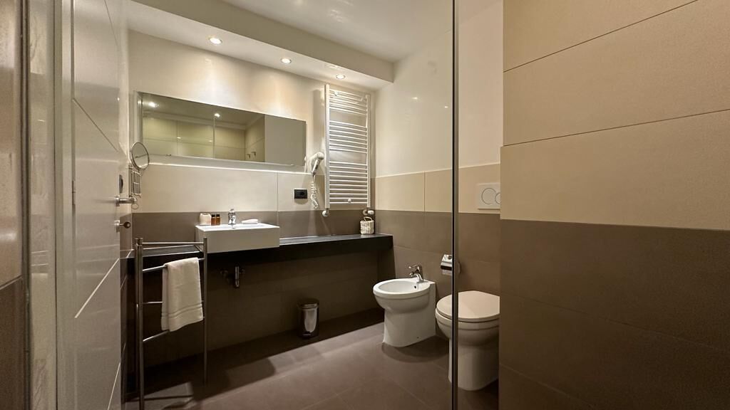 Une salle de bain moderne avec une douche à parois de verre, un meuble-lavabo avec un miroir, des toilettes et un bidet.