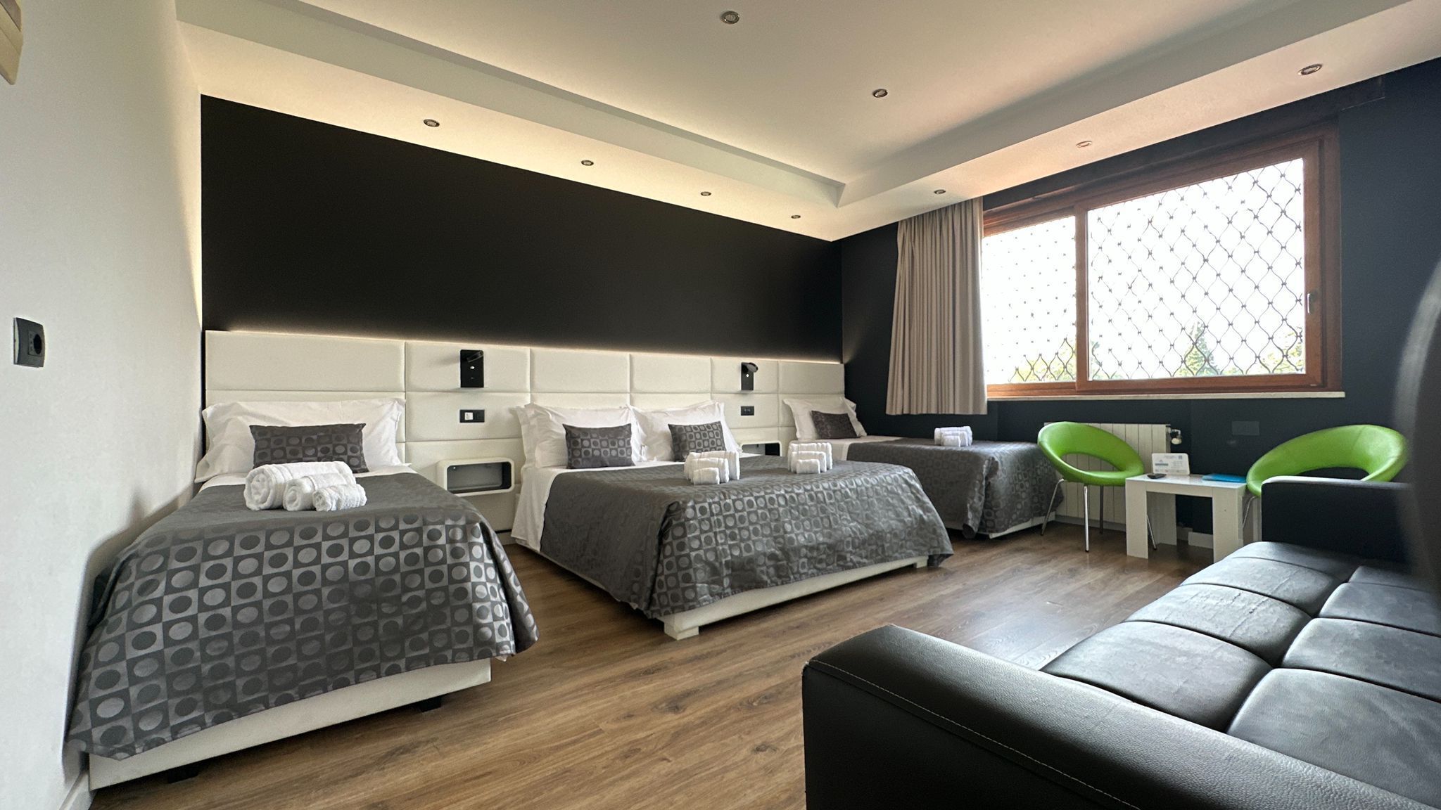 Una habitación de hotel moderna con dos camas, un sofá, un escritorio y una ventana con vistas.