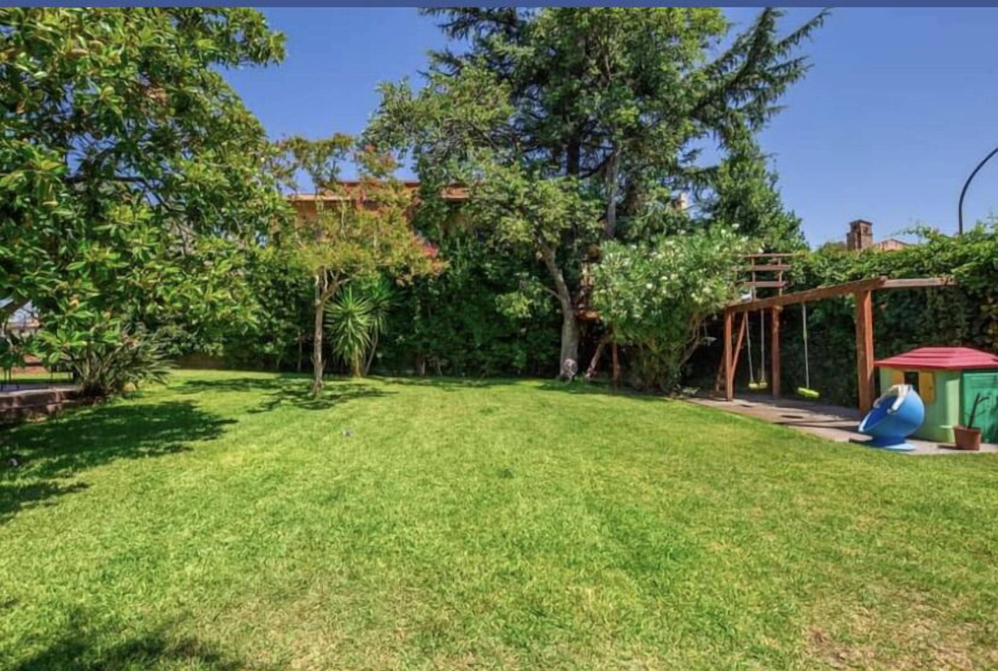 A well-maintained grassy yard with a wooden pergola and a swing set.
