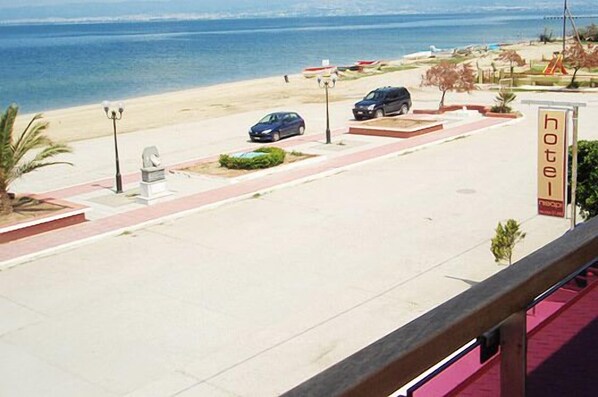 Un hotel con vista al mar, un estacionamiento con coches y un cartel que indica el nombre del hotel.
