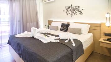 A neatly made bed with towels, a compass wall art, and a bedside table with a lamp.