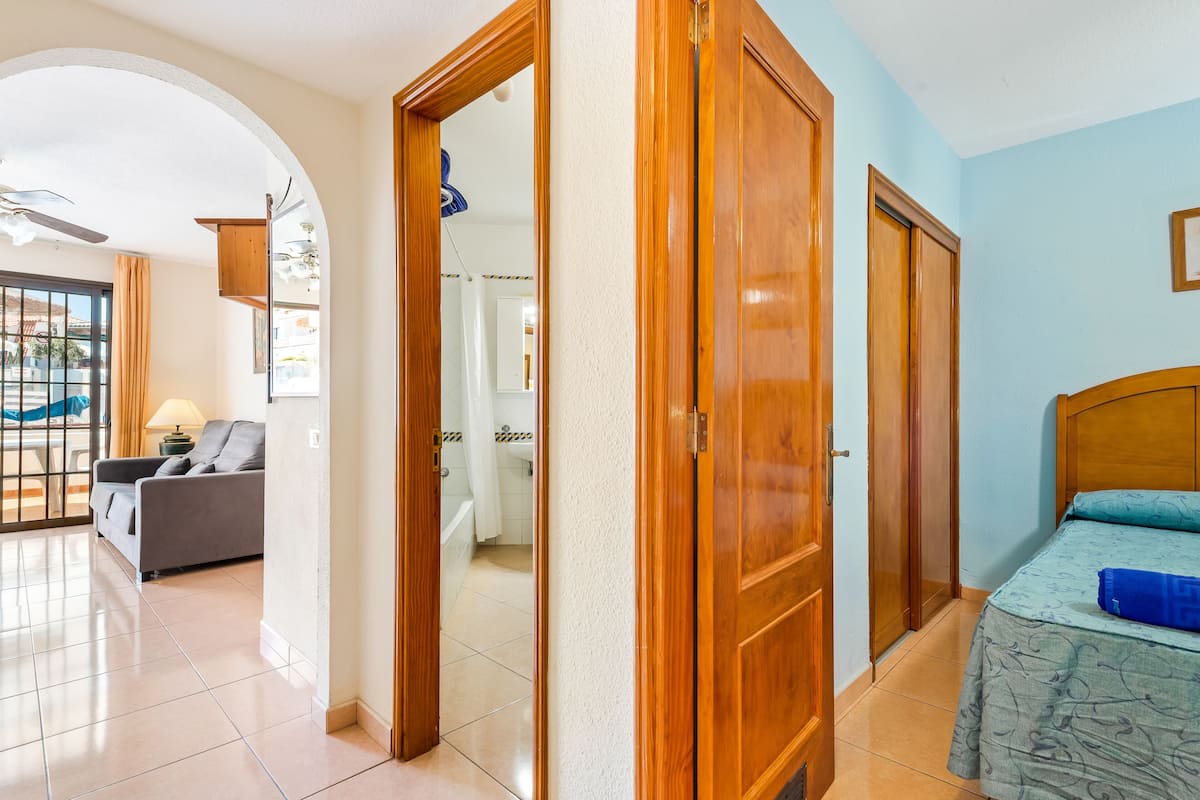 Une pièce comprenant un lit, un canapé et une salle de bain, visible à travers une porte ouverte.