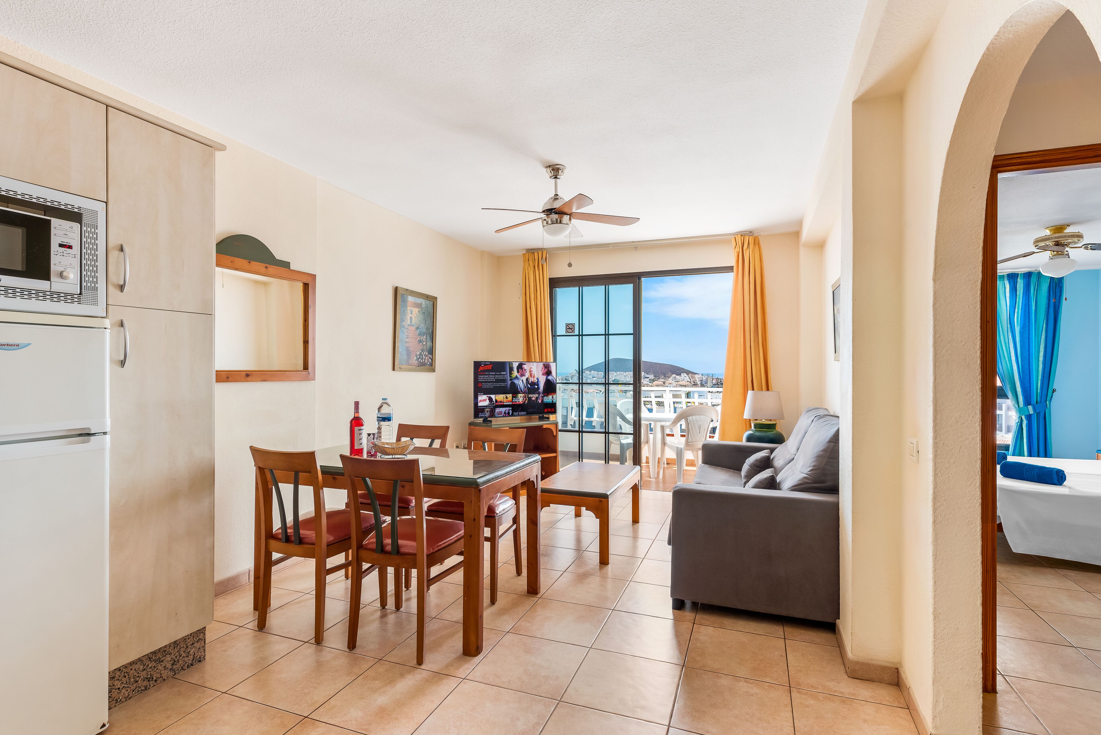 A compact living space with a kitchen, dining area, and a balcony with a view.