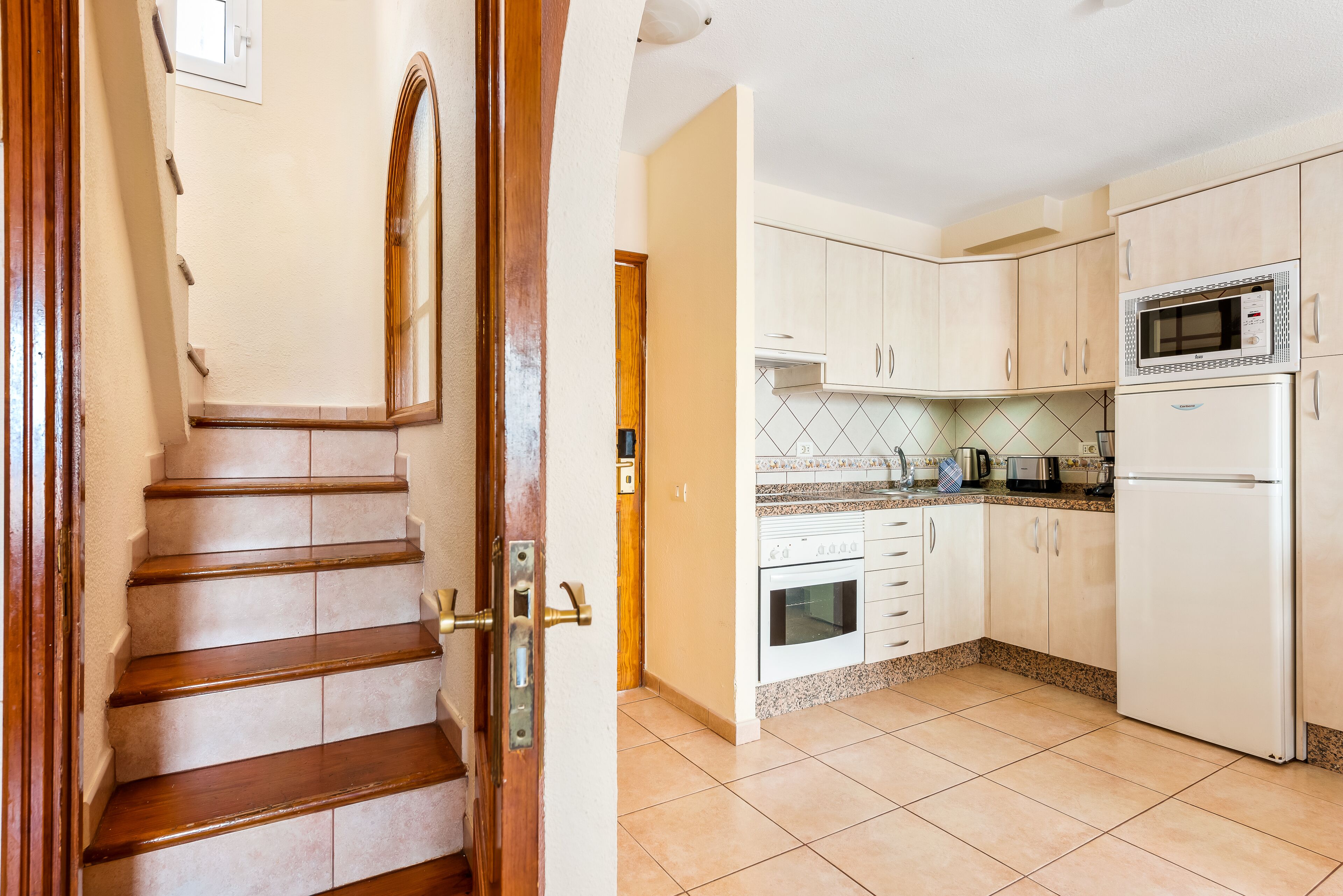 A kitchen with white cabinets, a microwave, and a refrigerator.