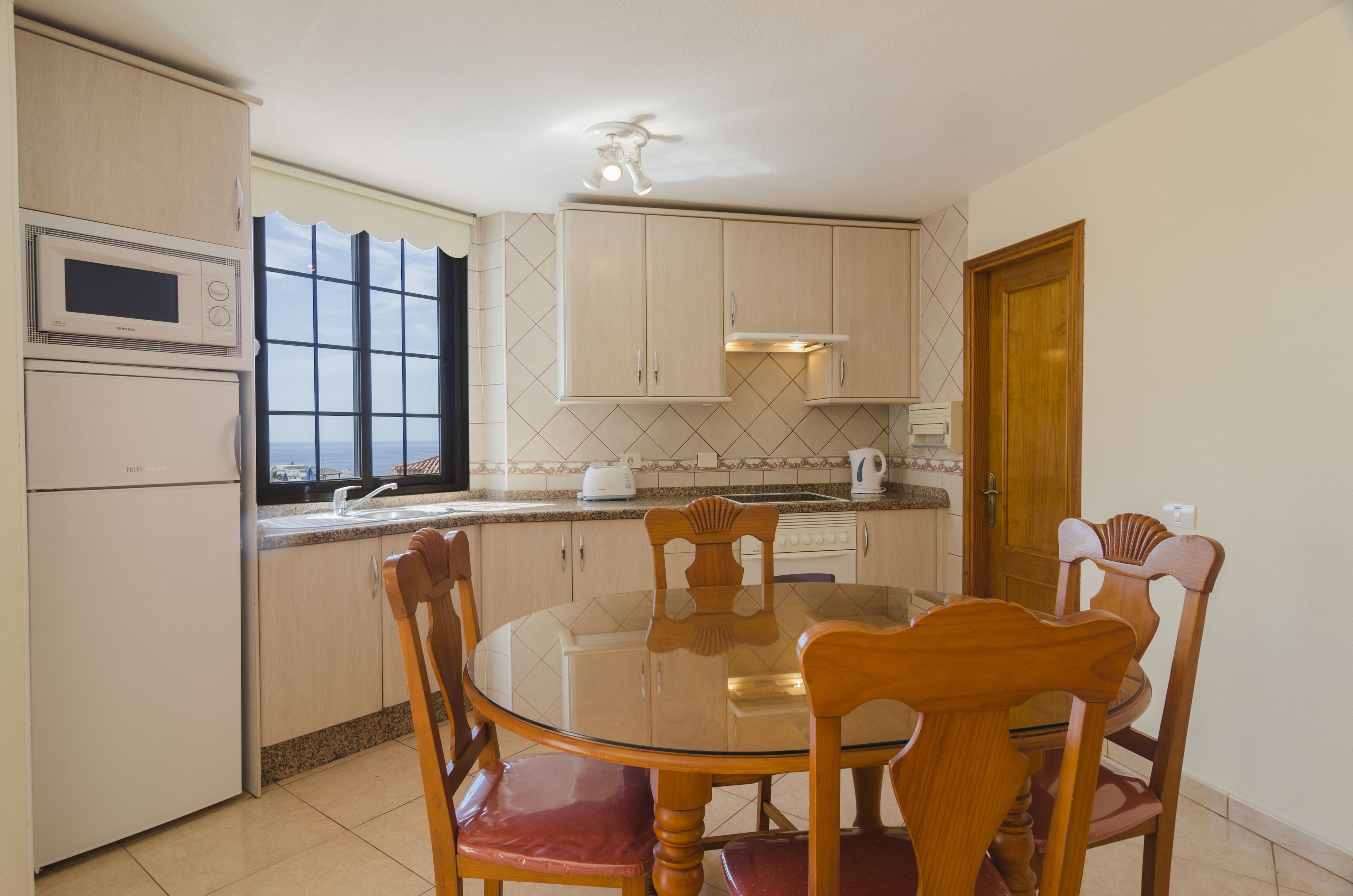 A kitchen with a dining table and chairs, a microwave, a toaster, and cabinets.