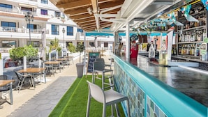 An outdoor bar area with a counter, seating, and a view of the building's exterior.
