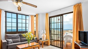 A living room with a sofa, coffee table, TV, and a balcony with a view.