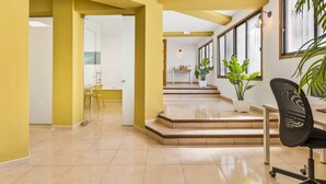 A spacious interior with yellow walls, a staircase leading to a kitchen area, and a seating area with a chair and a desk.