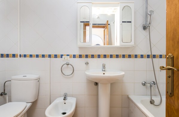 A bathroom with a toilet, bidet, sink, and bathtub.