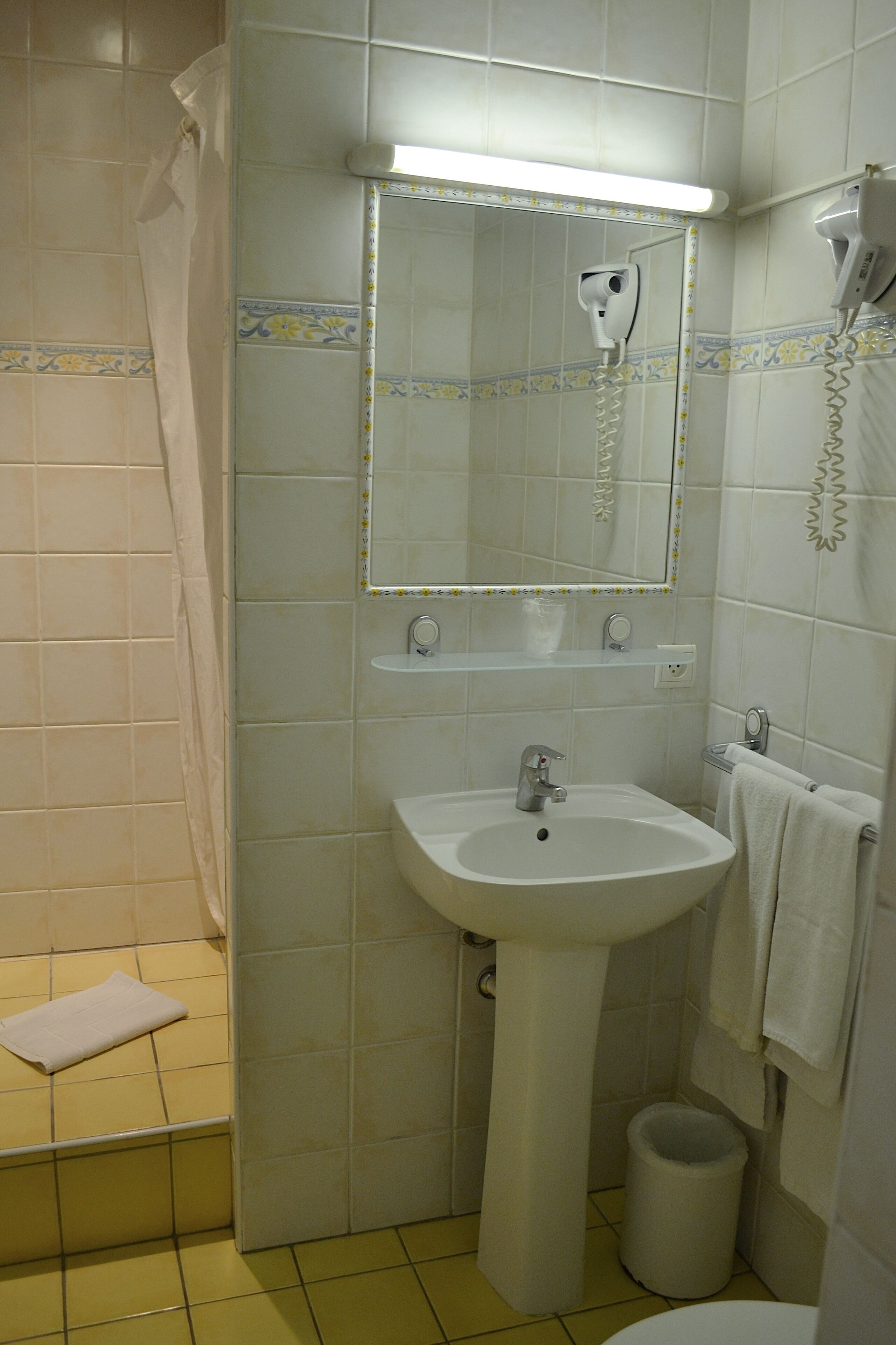 Un baño con lavamanos, espejo y secador de pelo.