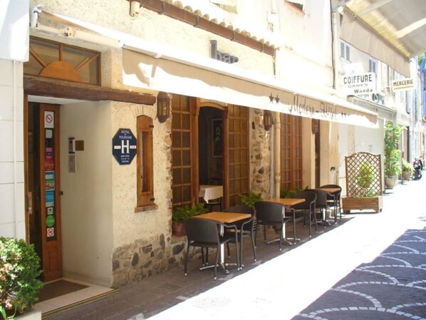 A hotel with outdoor seating, a sign indicating it is a hotel, and a visible entrance.