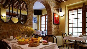A dining area with a stone wall, a table set with breakfast items, and a large window with a view. - Modern Hôtel (Antibes)