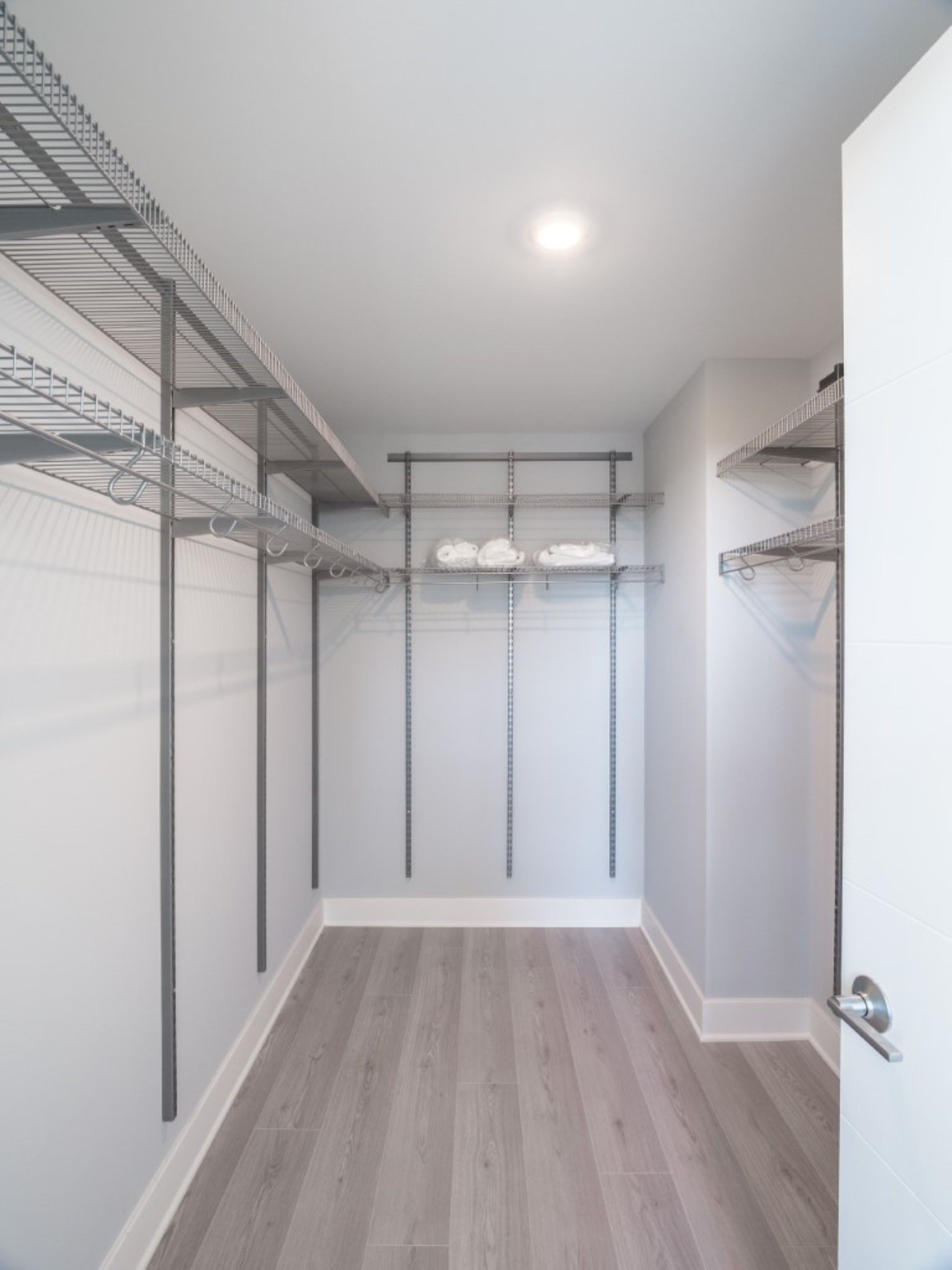 Un closet amplio con estanterías metálicas y piso de madera.