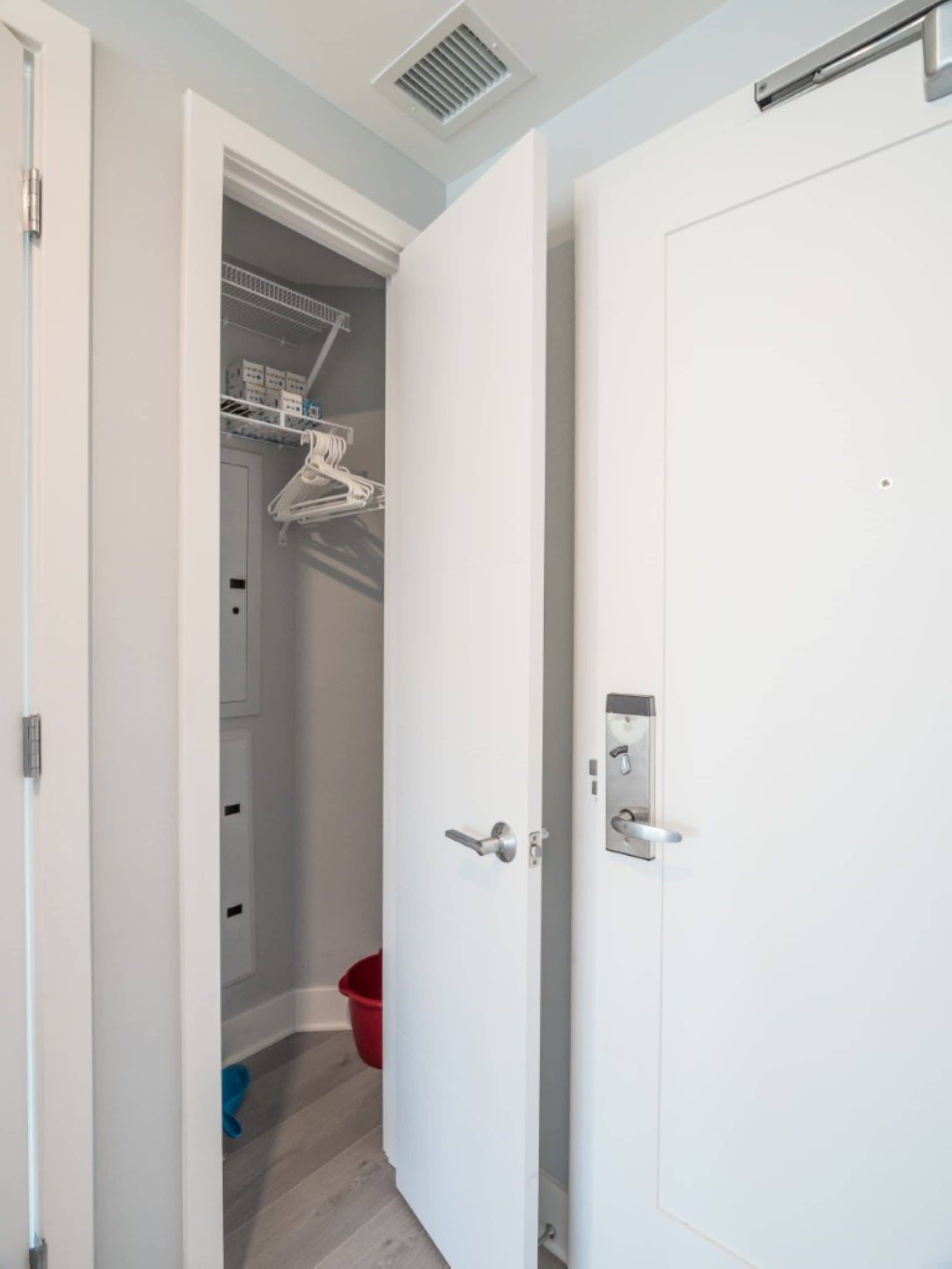 A walk-in closet with hanging space and a door with a handle and lock.