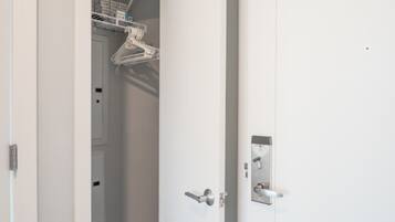 A walk-in closet with hanging space and a door with a handle and lock.