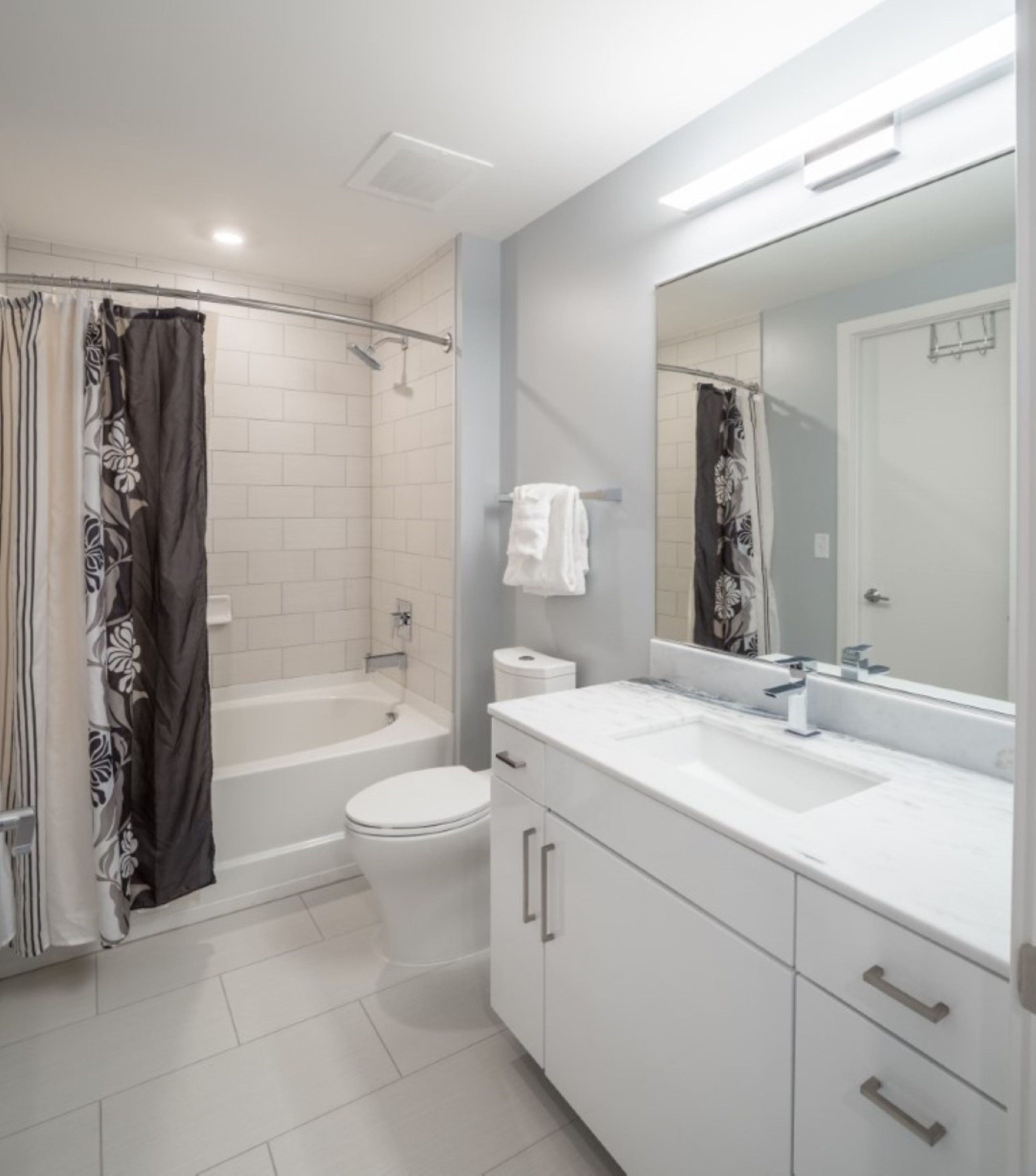 Een moderne badkamer met een bad, toilet en wastafel met een grote spiegel.