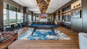 A modern indoor pool area with a pool table, seating, and a view of the outdoors. - Global Luxury Suites Bethesda Chevy Chase (Bethesda)